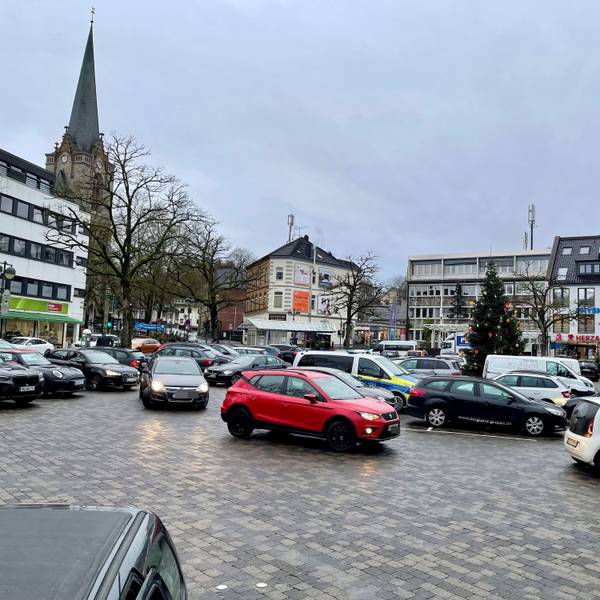 Eine gepflasterte Fläche, auf der Autos parken.