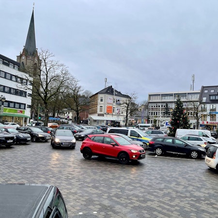 Eine gepflasterte Fläche, auf der Autos parken.