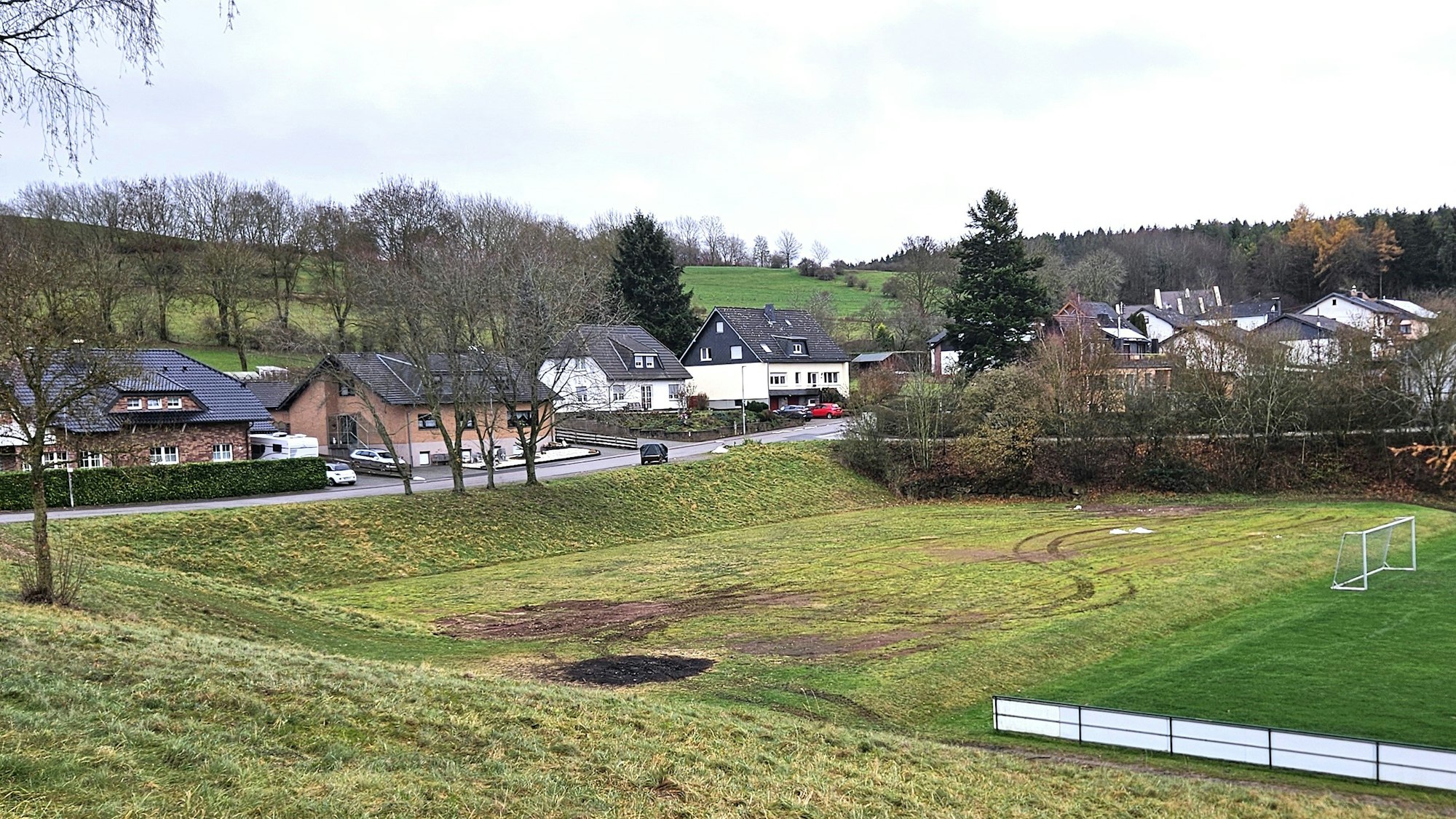 Blick auf die Fläche hinter dem Sportplatz und auf die Häuser der Anwohner.
