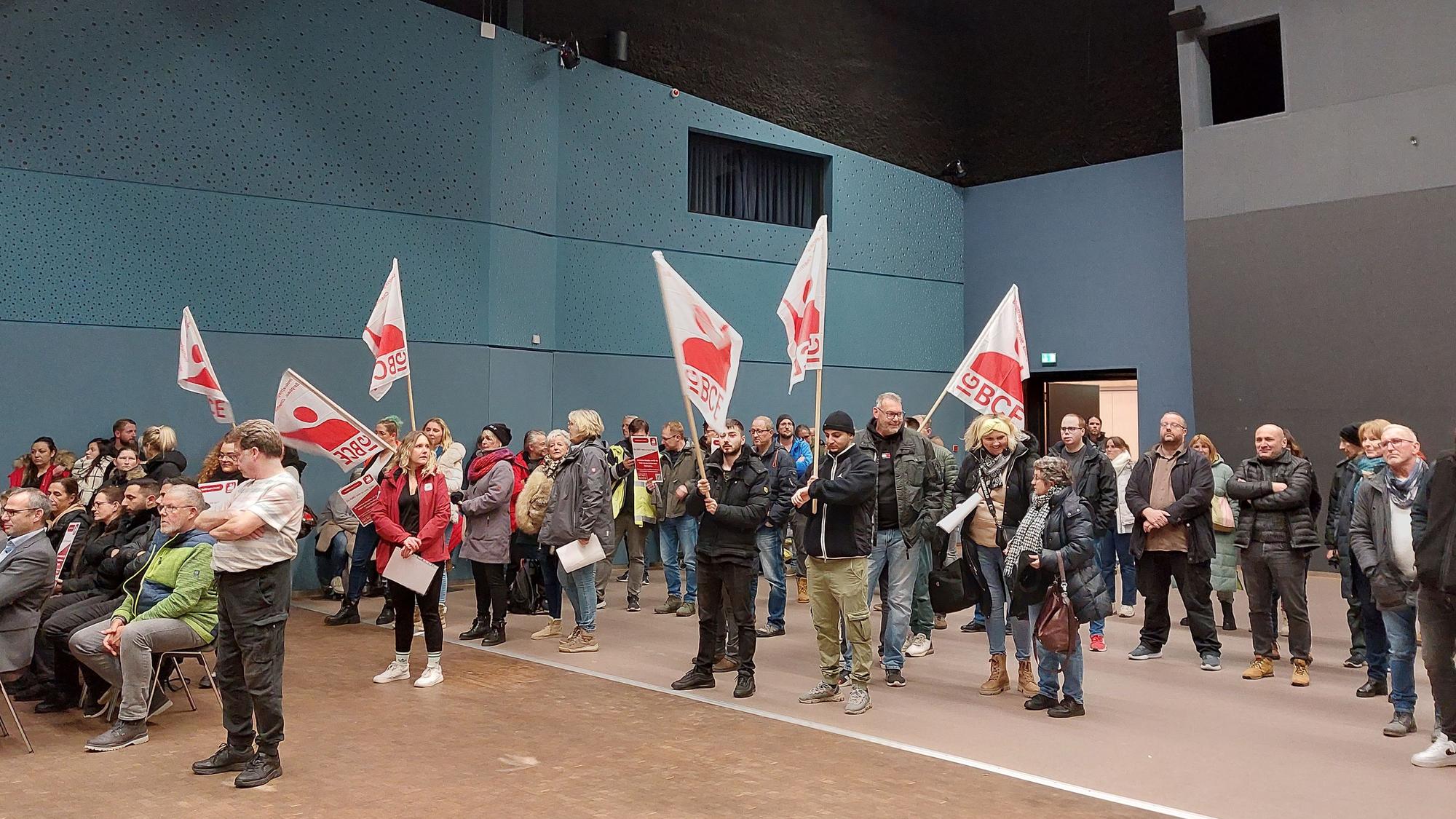 Menschen protestieren mit Fahnen in einer Stadtratssitzung.