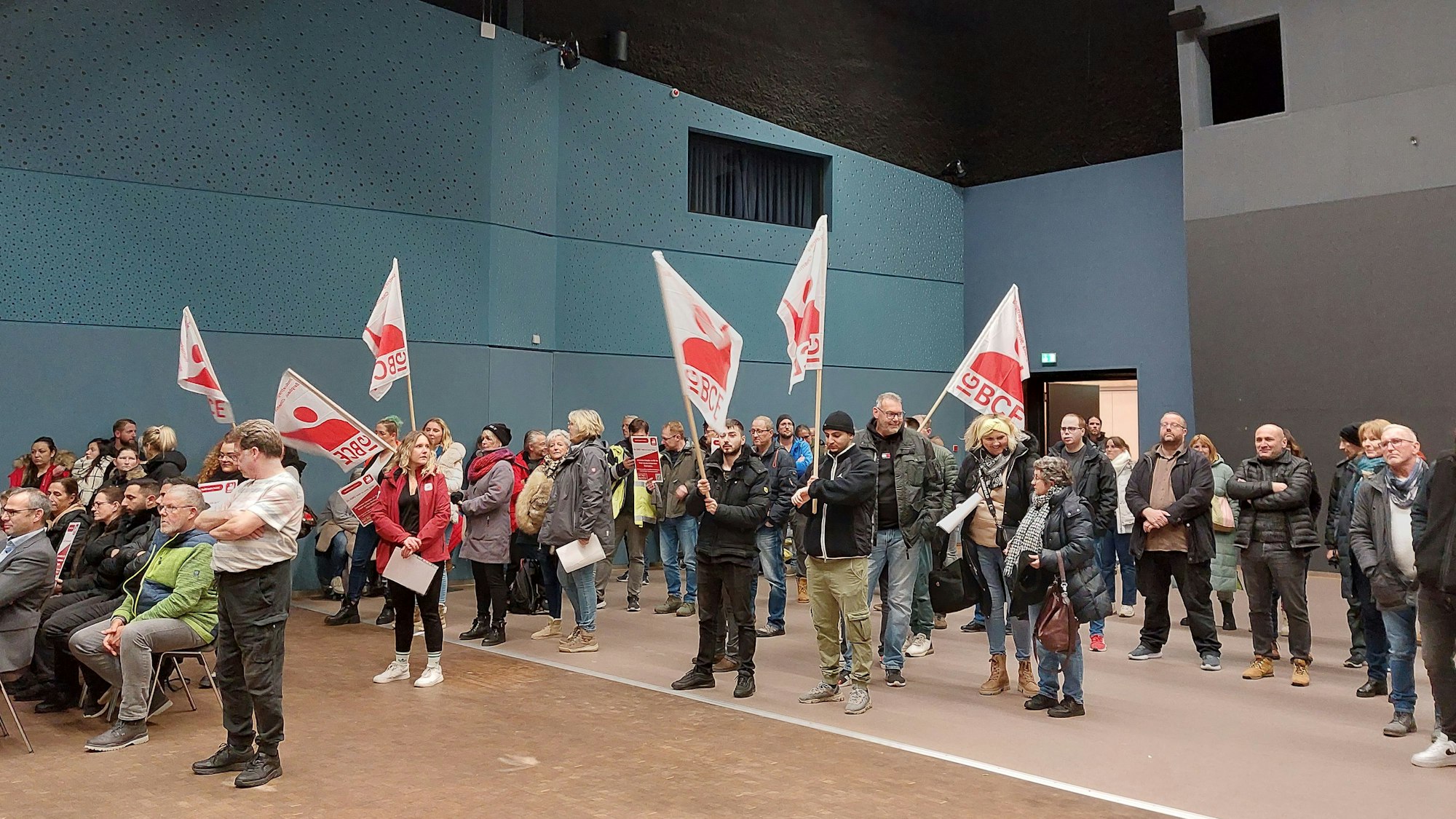 Menschen protestieren mit Fahnen in einer Stadtratssitzung.