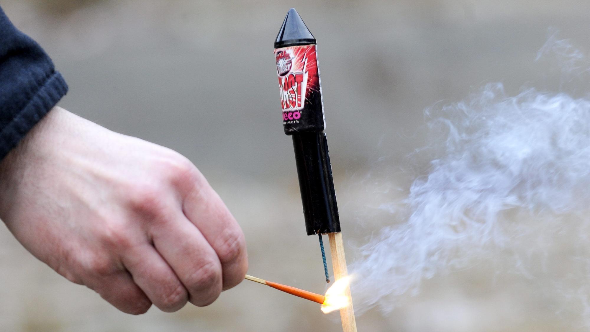 Ein Mann zündet die Zündschnur einer Silvesterrakete an. Feuerwehr und Polizei warnen vor leichtfertigem Umgang mit Böllern in der Silvesternacht.