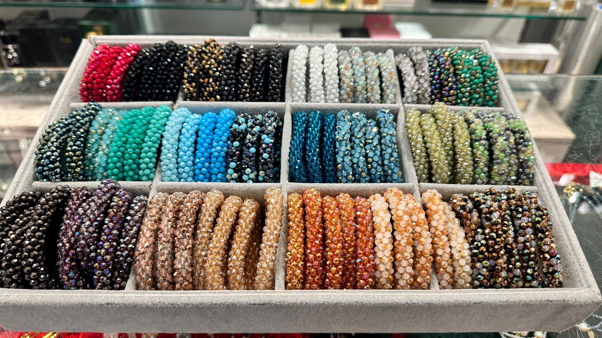 Schillernde, bunte Armbänder liegen in einer Auslage in der Parfümerie Pieper in Rodenkirchen.