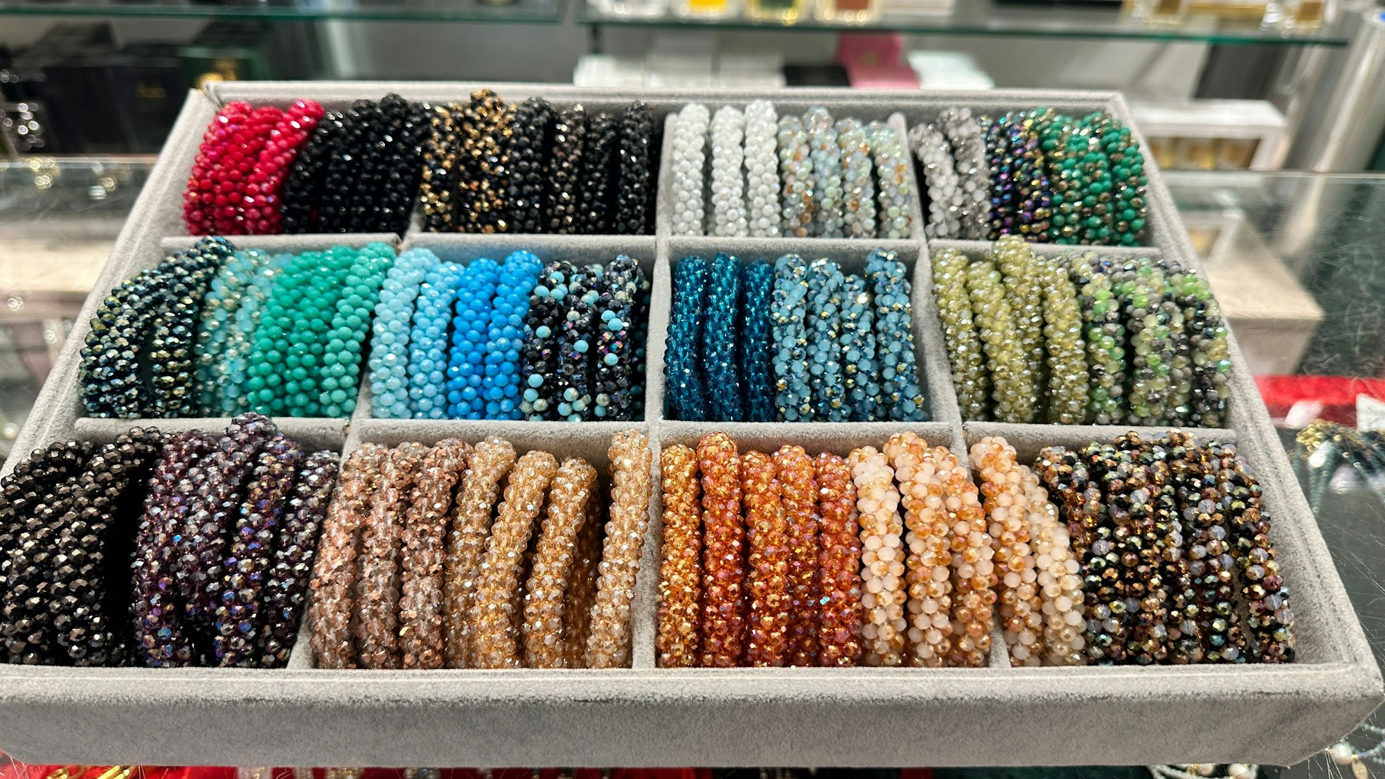Schillernde, bunte Armbänder liegen in einer Auslage in der Parfümerie Pieper in Rodenkirchen.