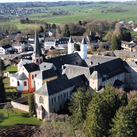 Das Luftbild zeigt das Gebäudeensemble des Klosters in Steinfeld. Im linken Bereich ist die Basilika mit ihren Türmen zu sehen.