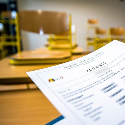 Eine Klassenlehrerin hält das Zeugnis eines Schülers einer Schule in Gütersloh hoch.