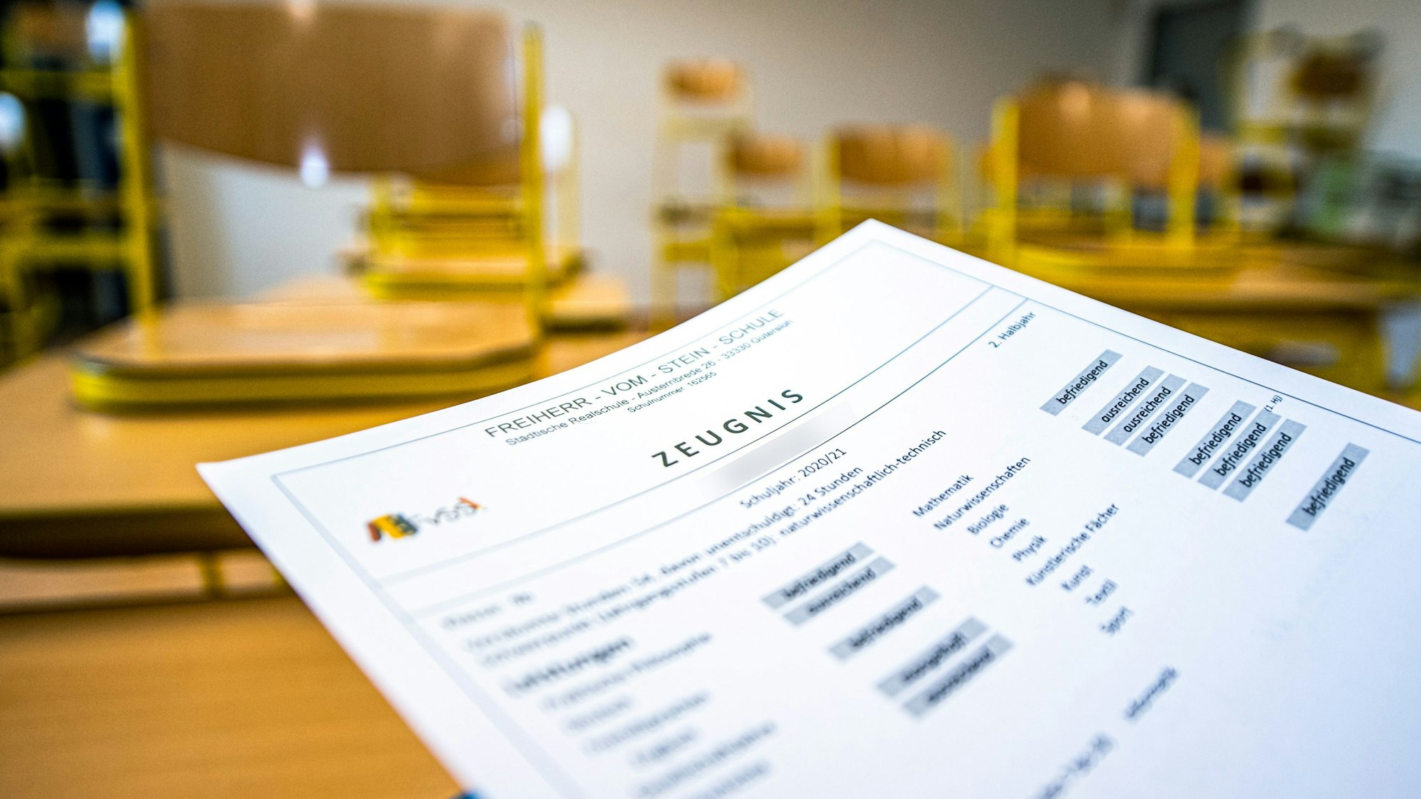 Eine Klassenlehrerin hält das Zeugnis eines Schülers einer Schule in Gütersloh hoch.