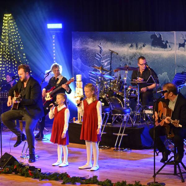 Romi und Lioli stehen in roten Kleidern mit den Paveiern auf der weihnachtlich geschmückten Bühne des Euskirchener Stadttheaters.