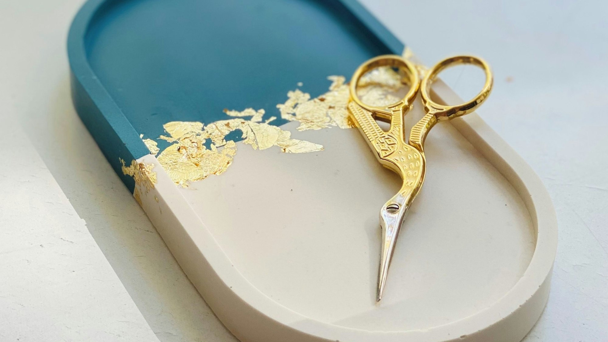 Auf einer Jesmonite-Schale liegt eine goldene Schere.