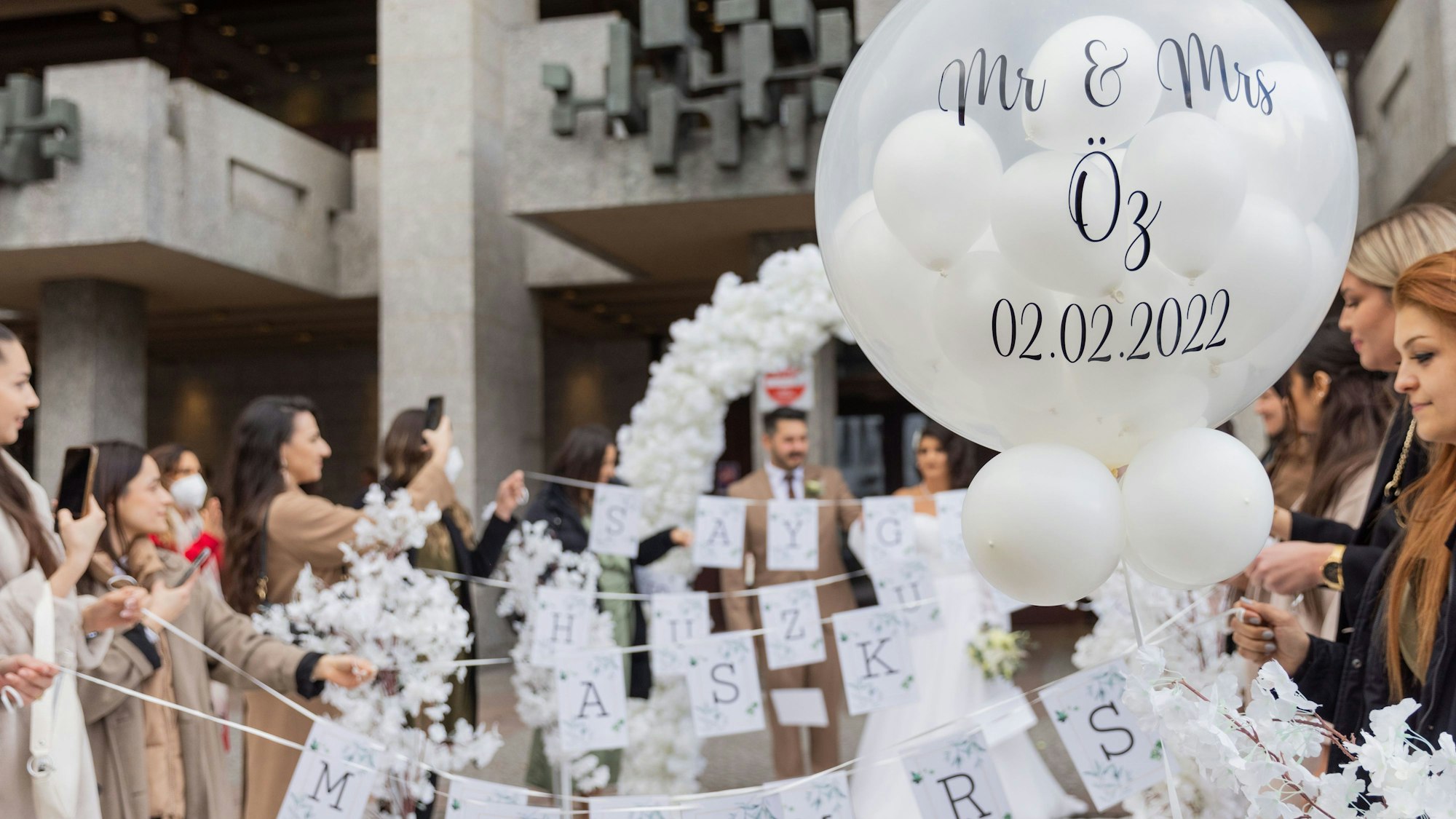 Eine große Hochzeitsgesellschaft vor dem historischen Rathaus in Köln.