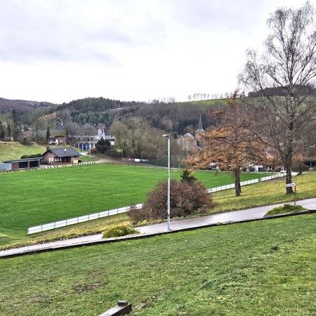 Zu sehen ist ein Blick vom Hang auf den Sötenicher Sportplatz.