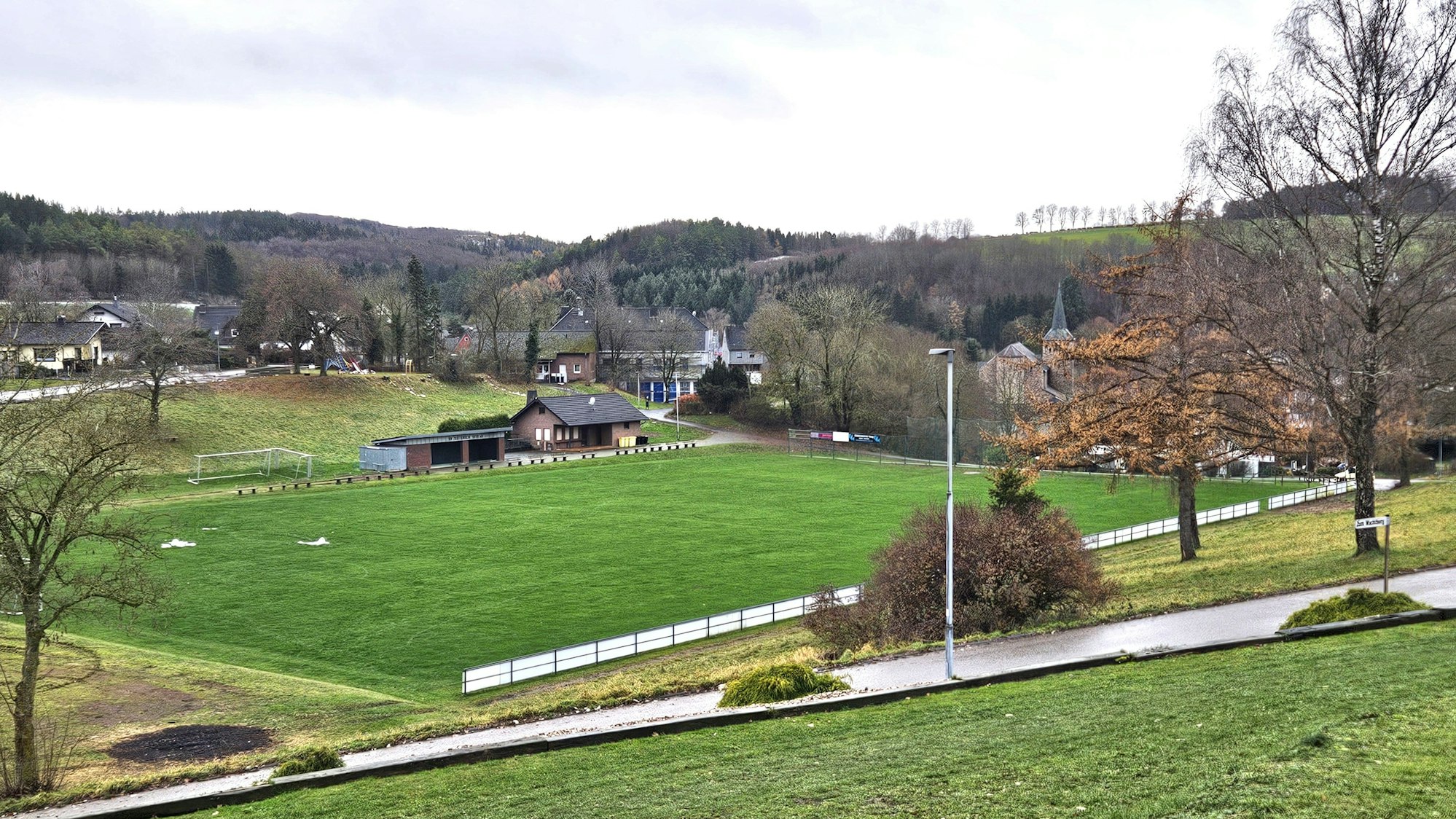 Zu sehen ist ein Blick vom Hang auf den Sötenicher Sportplatz.