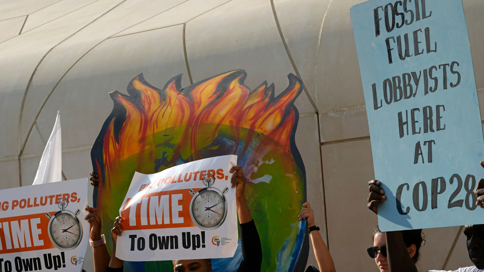 Demonstranten halten Plakate mit der Aufschrift ‚big polluters, time to own up‘ nehmen an einer Demonstration gegen fossile Brennstoffe während der Weltklimakonferenz der Vereinten Nationen (COP28) teil.