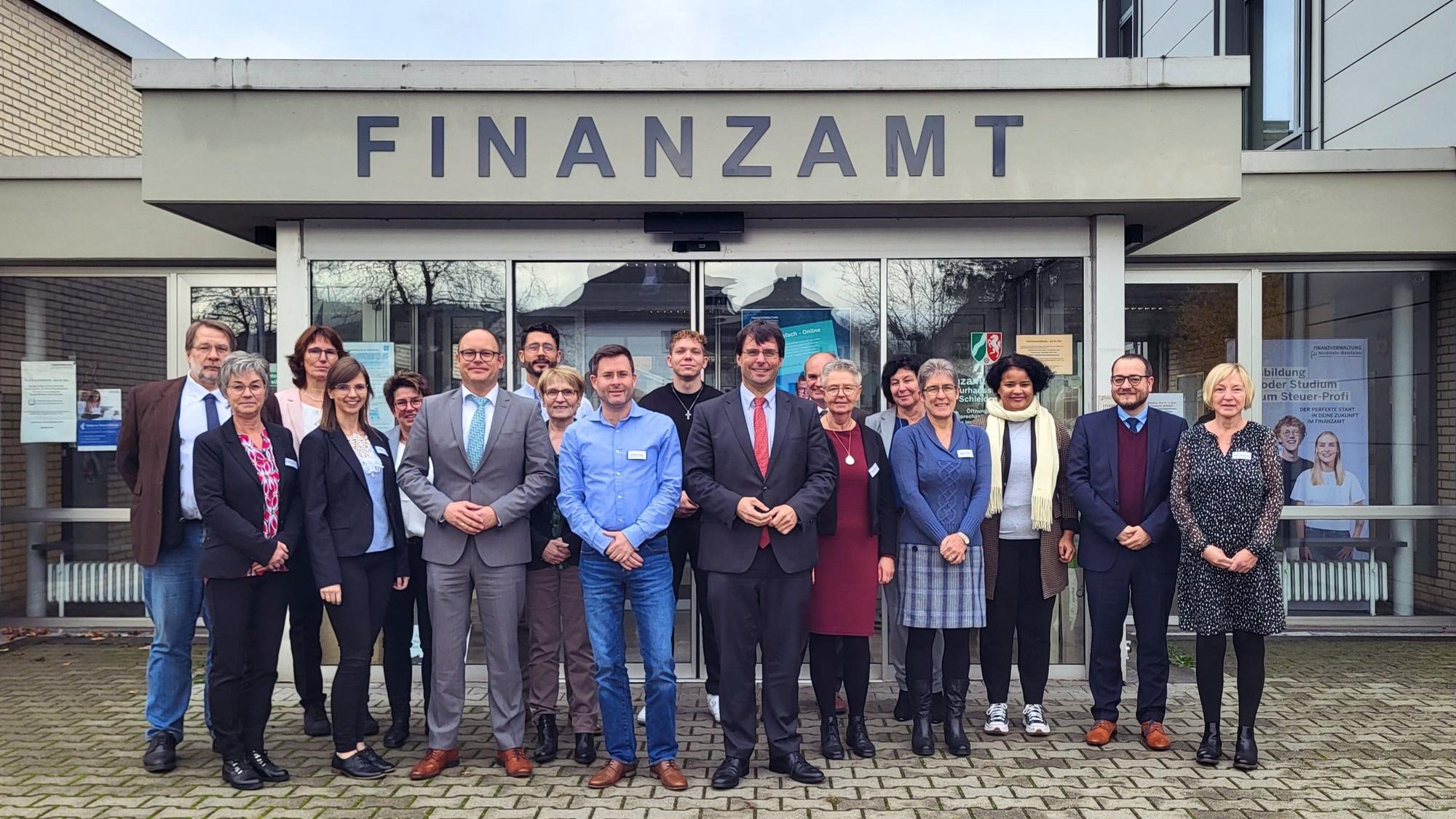 Finanzminister Dr. Marcus Optendrenk steht mit zahlreichen Vertretern des Finanzamts vor dem Eingang des Schleidener Finanzamts.