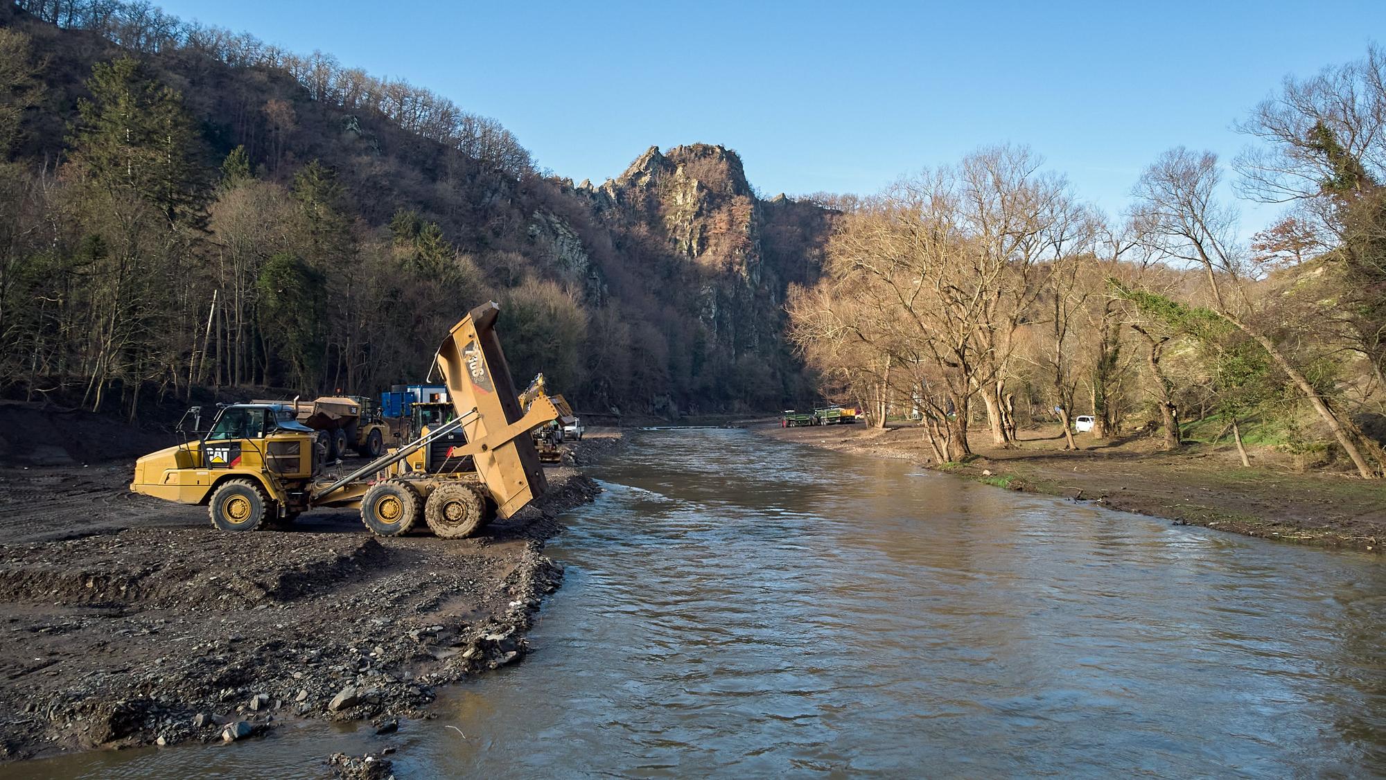 Baumaschinen stehen an der Ahrtalschleife bei Altenahr am Flussufer.