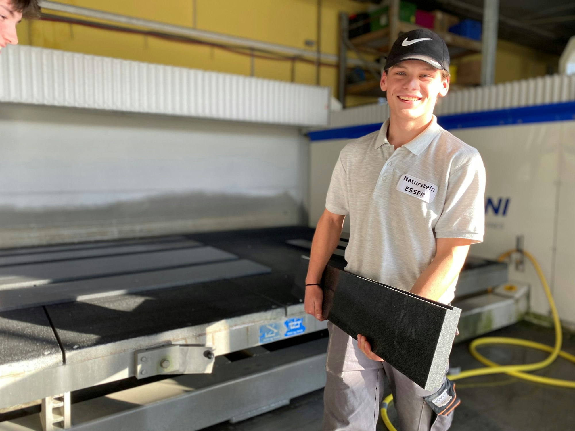 Der Auszubildende Pascal Elschenbroich trägt eine Fensterbank aus Naturstein.