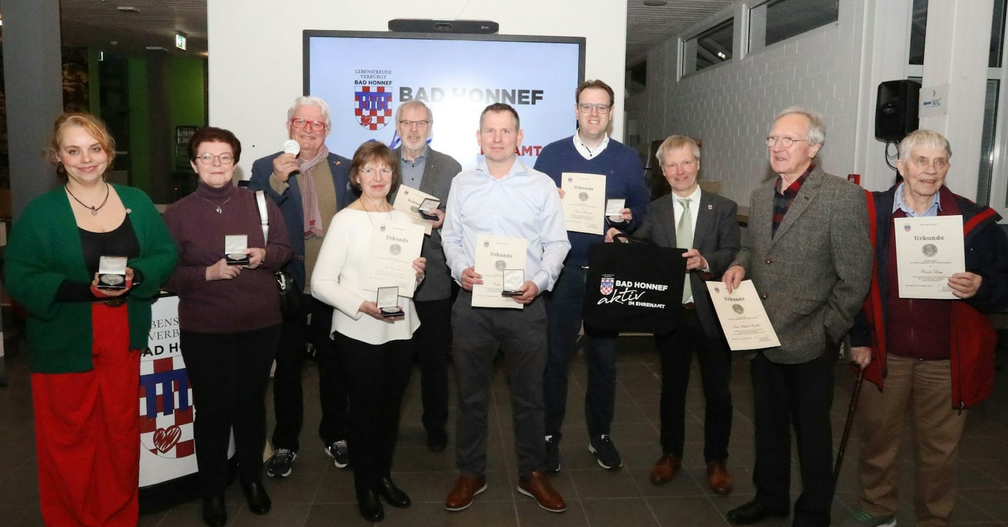 Eine Gruppe von Männern und Frauen zeigen ihre Urkunden und die Dankmedaillen.