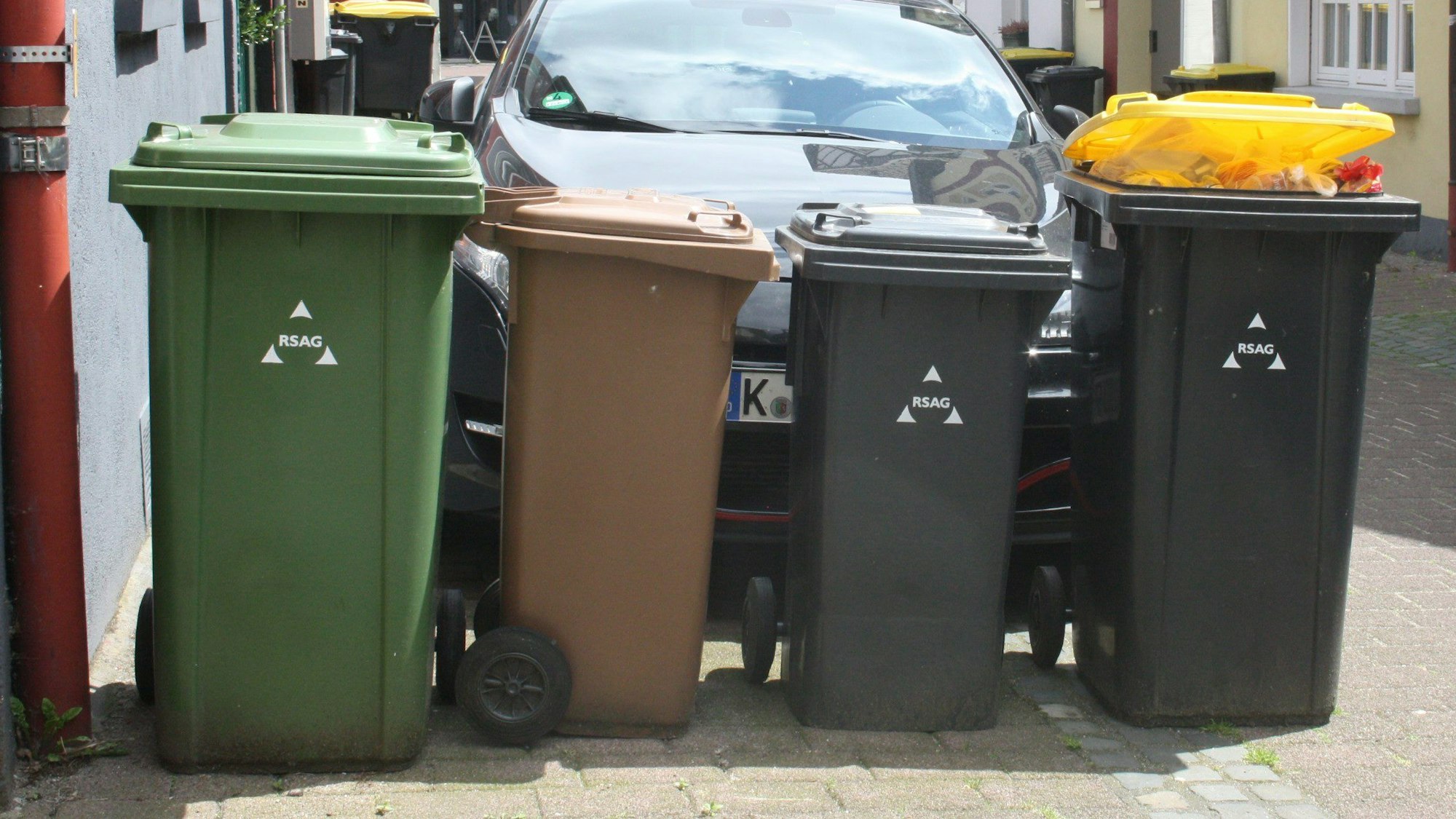 Auf einer Straße in Siegburg stehen vier Mülltonnen.