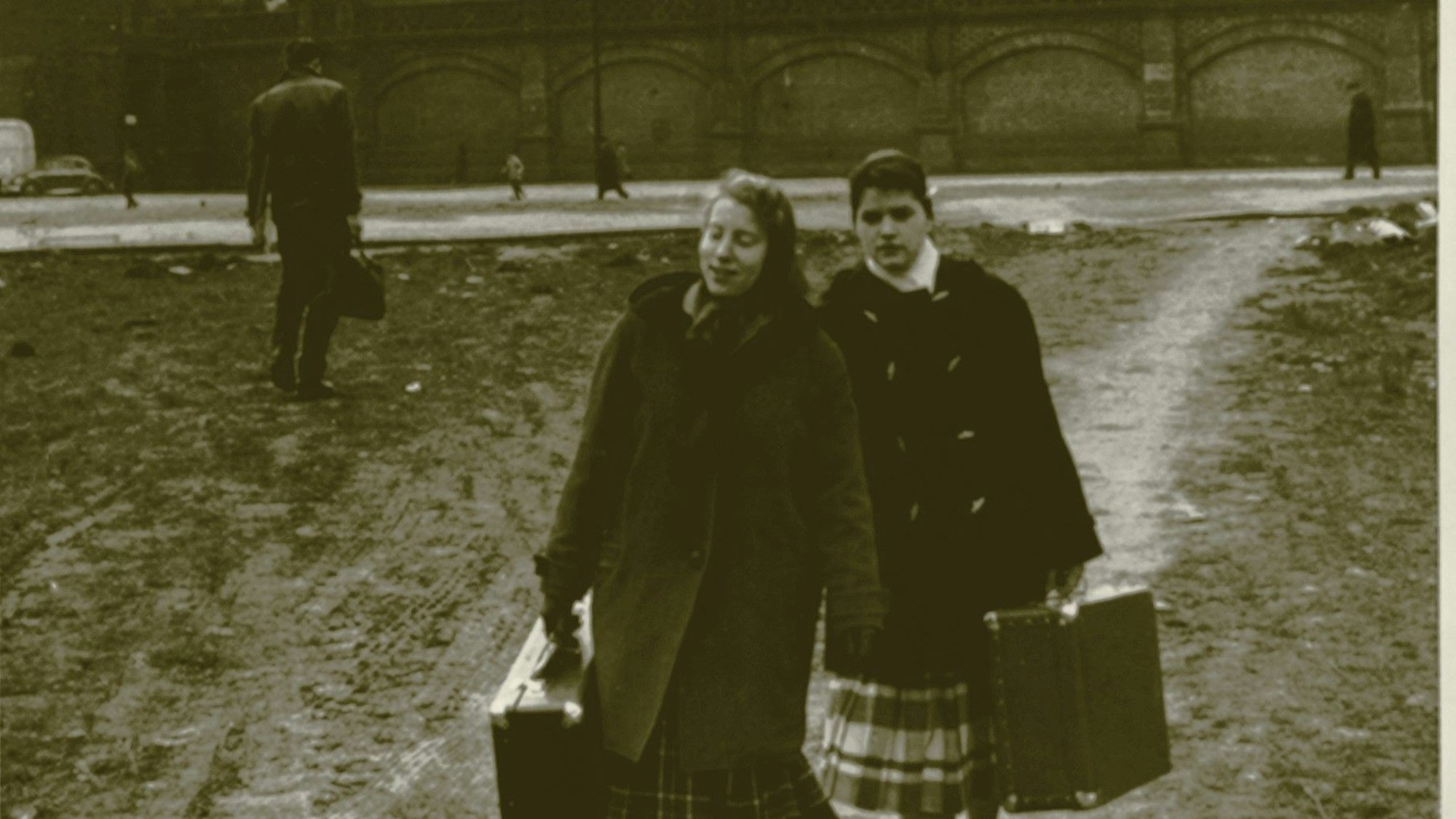 Zwei junge Frauen laufen mit je einem Koffer in der Hand über einen matschigen Platz am Hauptbahnhof.