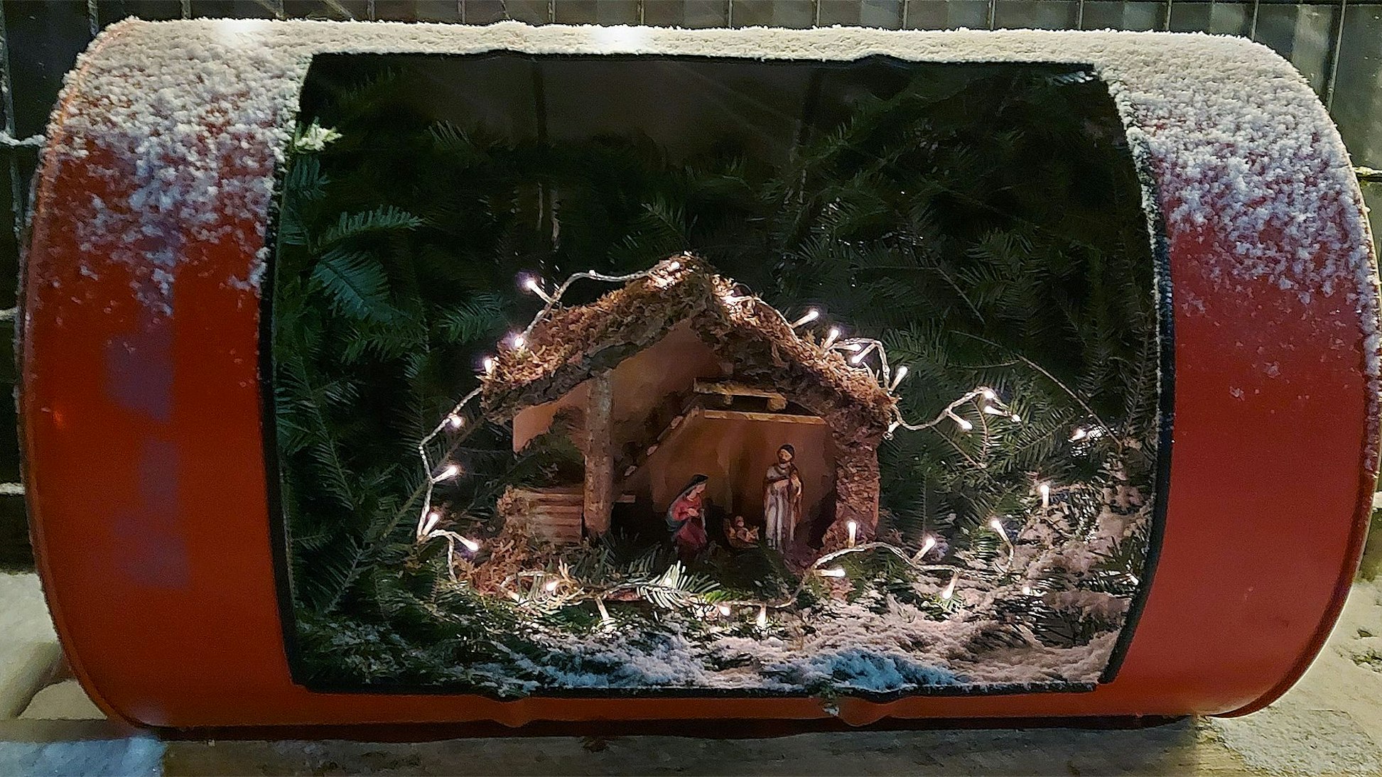 Ein altes Ölfass ist aufgeschnitten. Darin befindet sich nun eine Weihnachtskrippe.