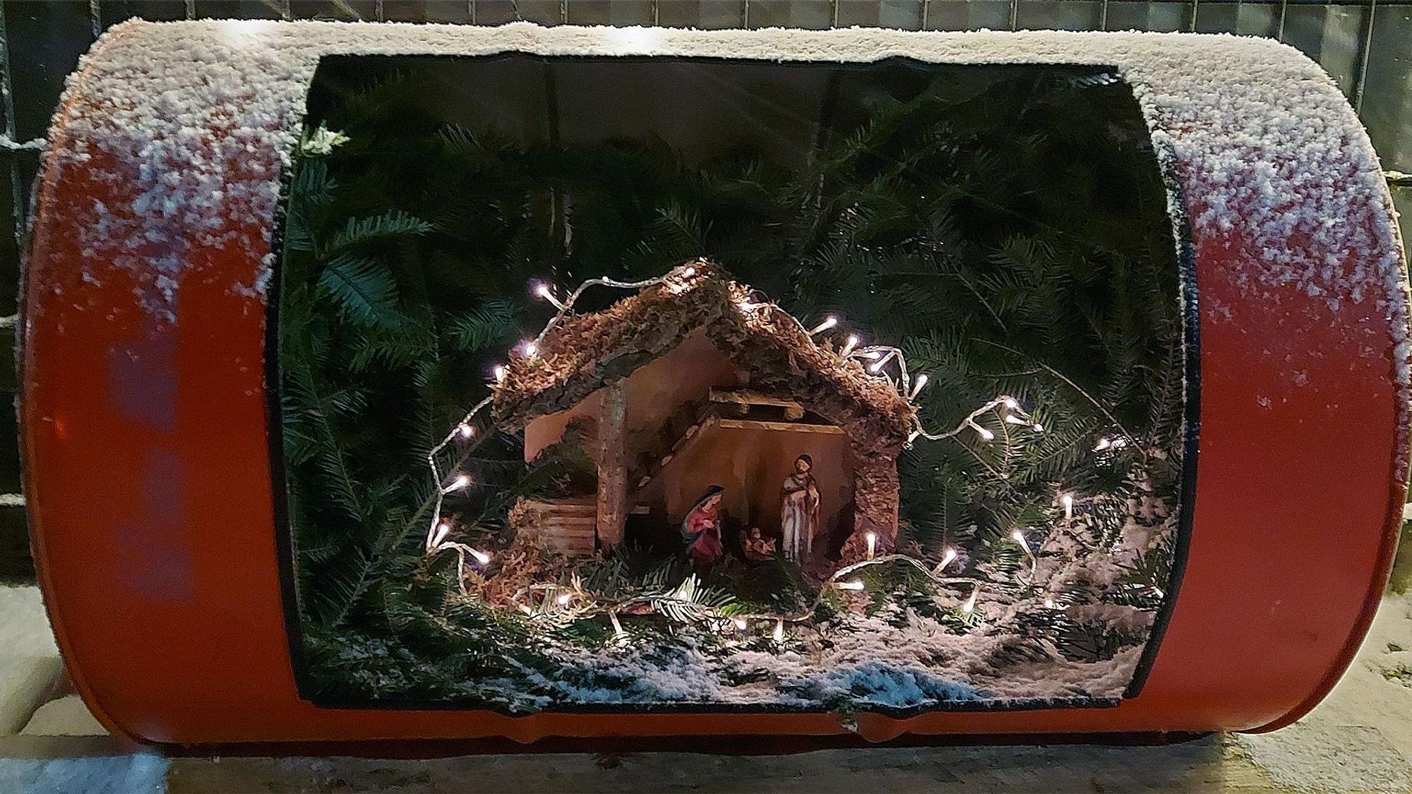 Ein altes Ölfass ist aufgeschnitten. Darin befindet sich nun eine Weihnachtskrippe.