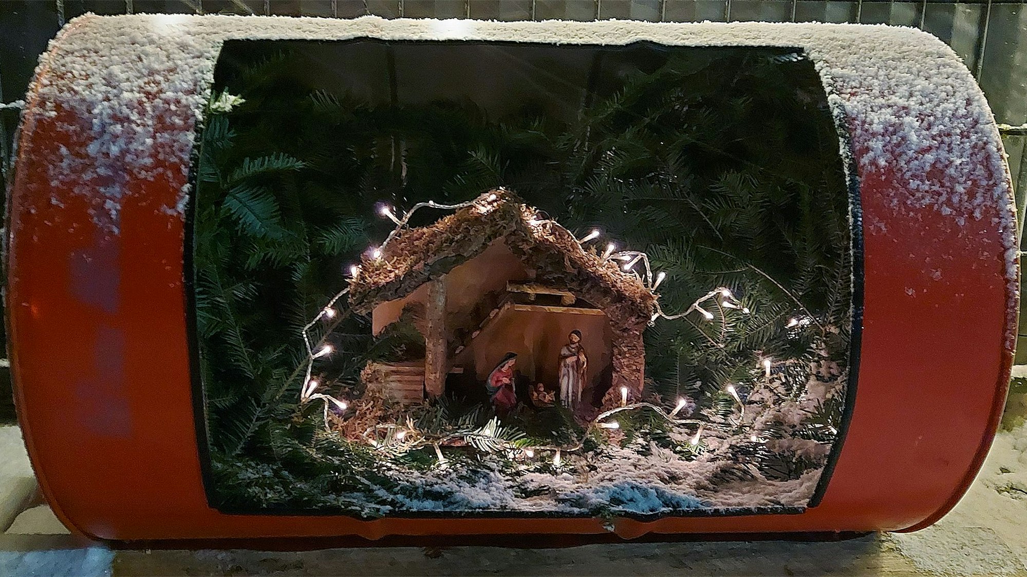 Ein altes Ölfass ist aufgeschnitten. Darin befindet sich nun eine Weihnachtskrippe.