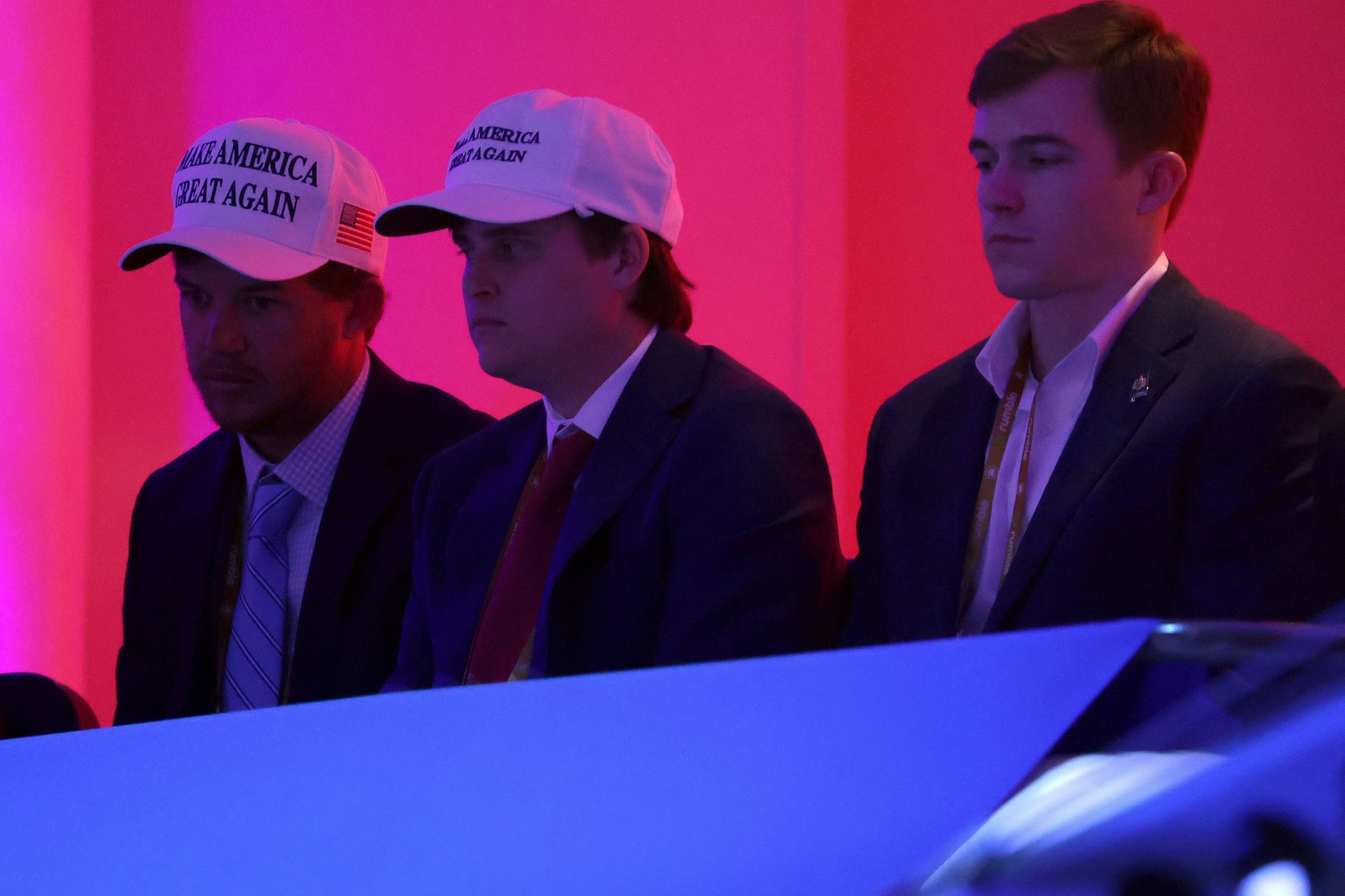 Männer mit Trump-Kappen sitzen im Publikum der Debatte.