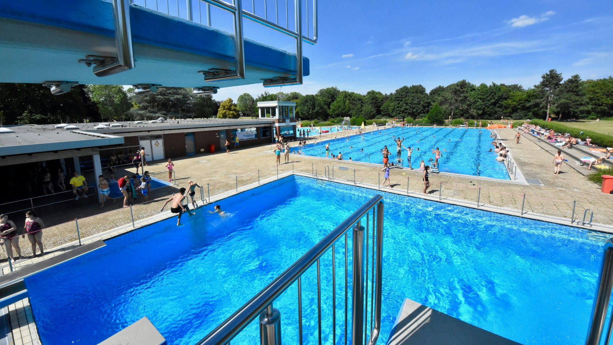 Blick auf den hohen Sprungturm und die blauen Becken des Freibades in Sankt Augustin.