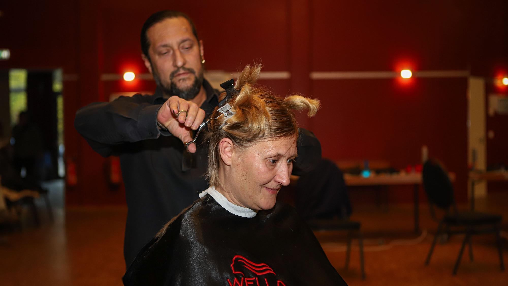 Ein Frisör schneidet einer Frau die Haare.