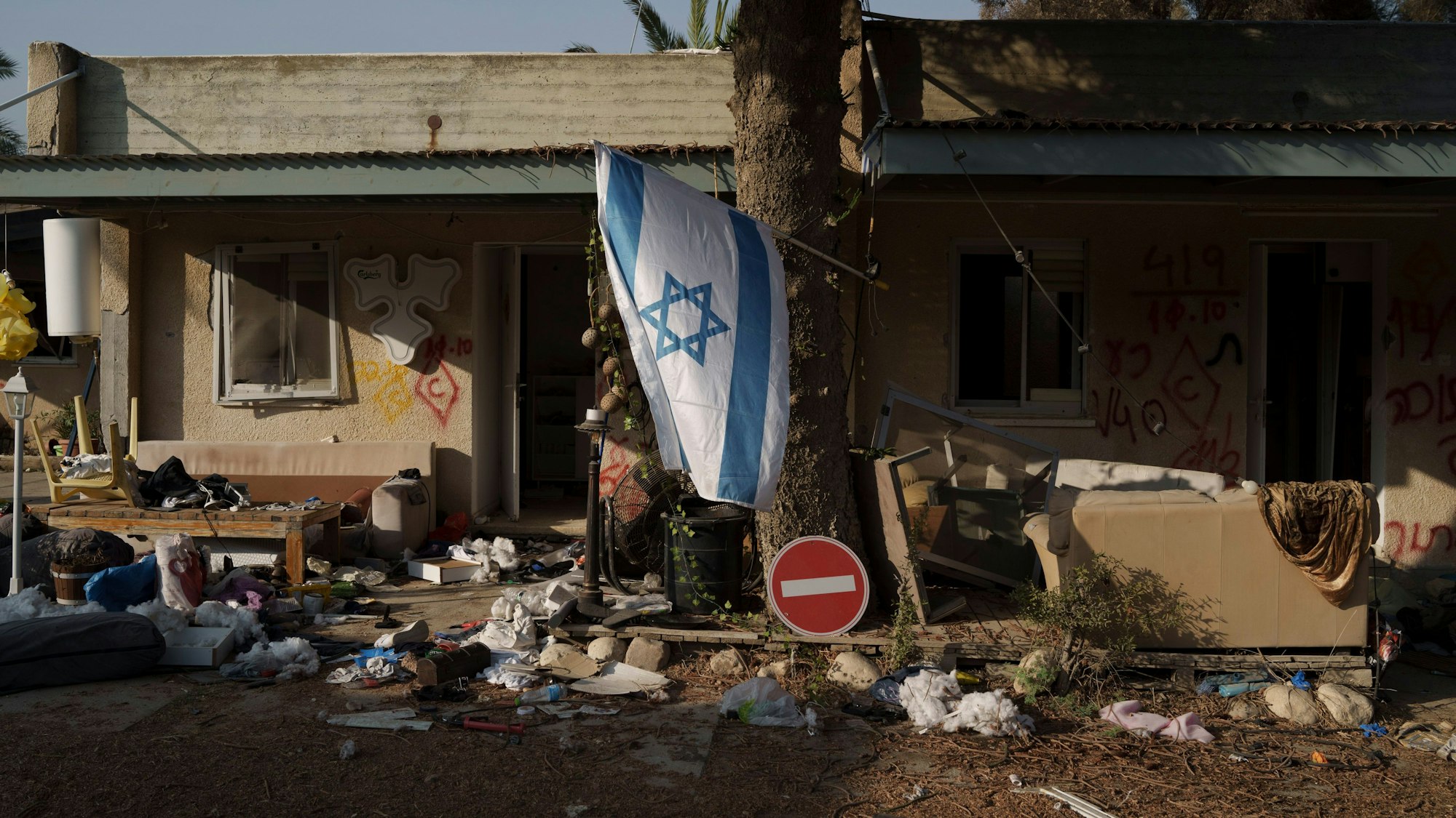 Kfar Azza: Eine israelische Flagge hängt im Kibbuz Kfar Azza in der Nähe des Gazastreifens zwischen zerstörten Häusern.