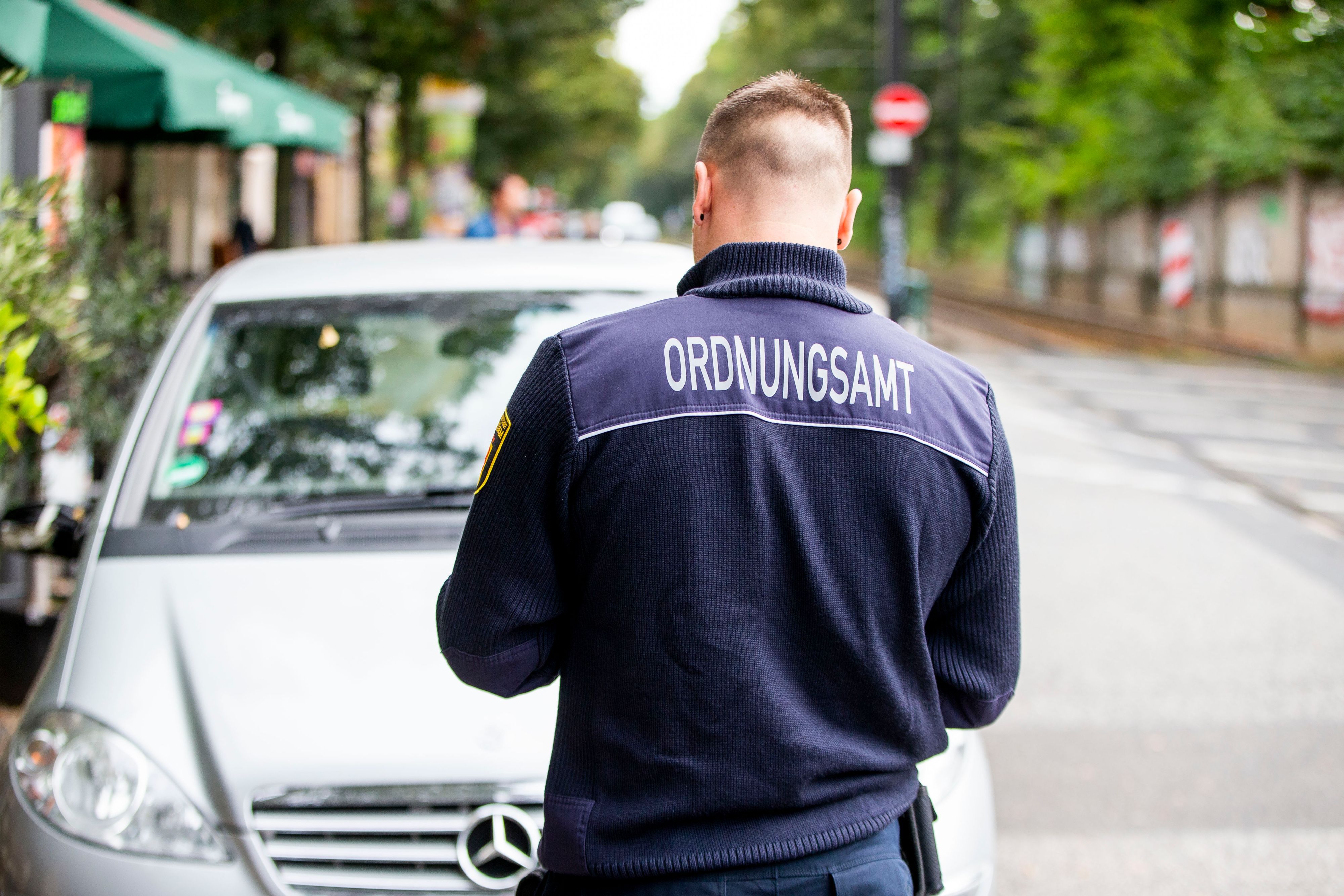 Angestellter des Ordnungsamtes notiert Falschparker.