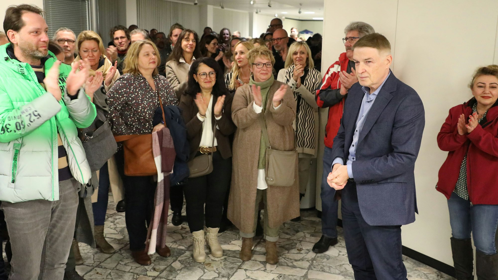 Kreisdirektor Dr. Erik Werdel steht im Foyer des Kreishauses Am Rübezahlwald. Menschen applaudieren ihm.
