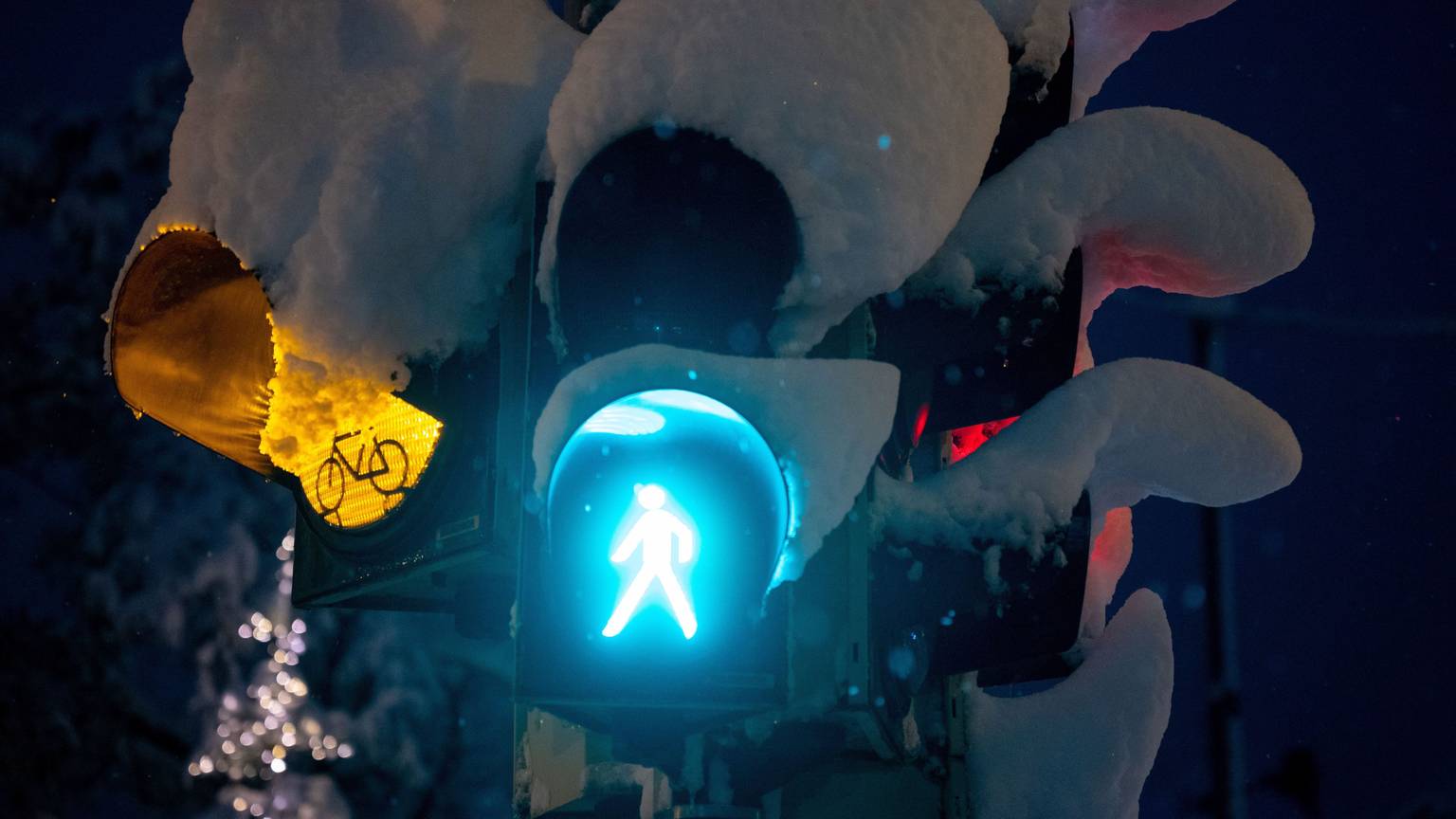 Schnee liegt auf einer Ampel an einer Kreuzung.