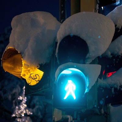 Schnee liegt auf einer Ampel an einer Kreuzung.