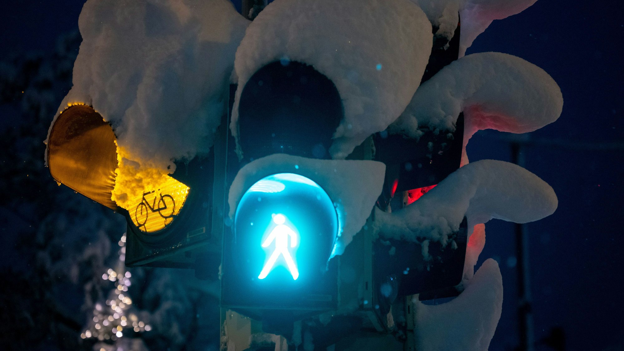 Schnee liegt auf einer Ampel an einer Kreuzung.