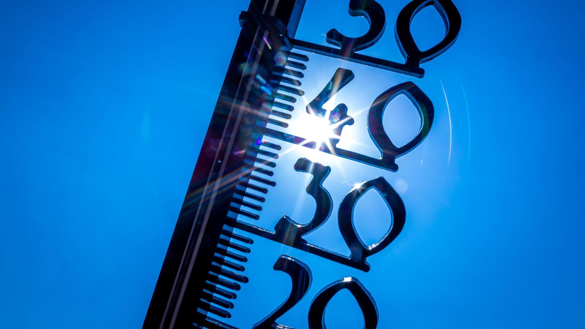 Ein Thermometer vor einem blauen Himmel und gleißender Sonne.