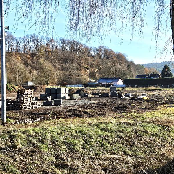 Blick auf den ehemaligen Sportplatz in Kall, auf dem Paletten, Pflastersteine und Erdhügel zu sehen sind.