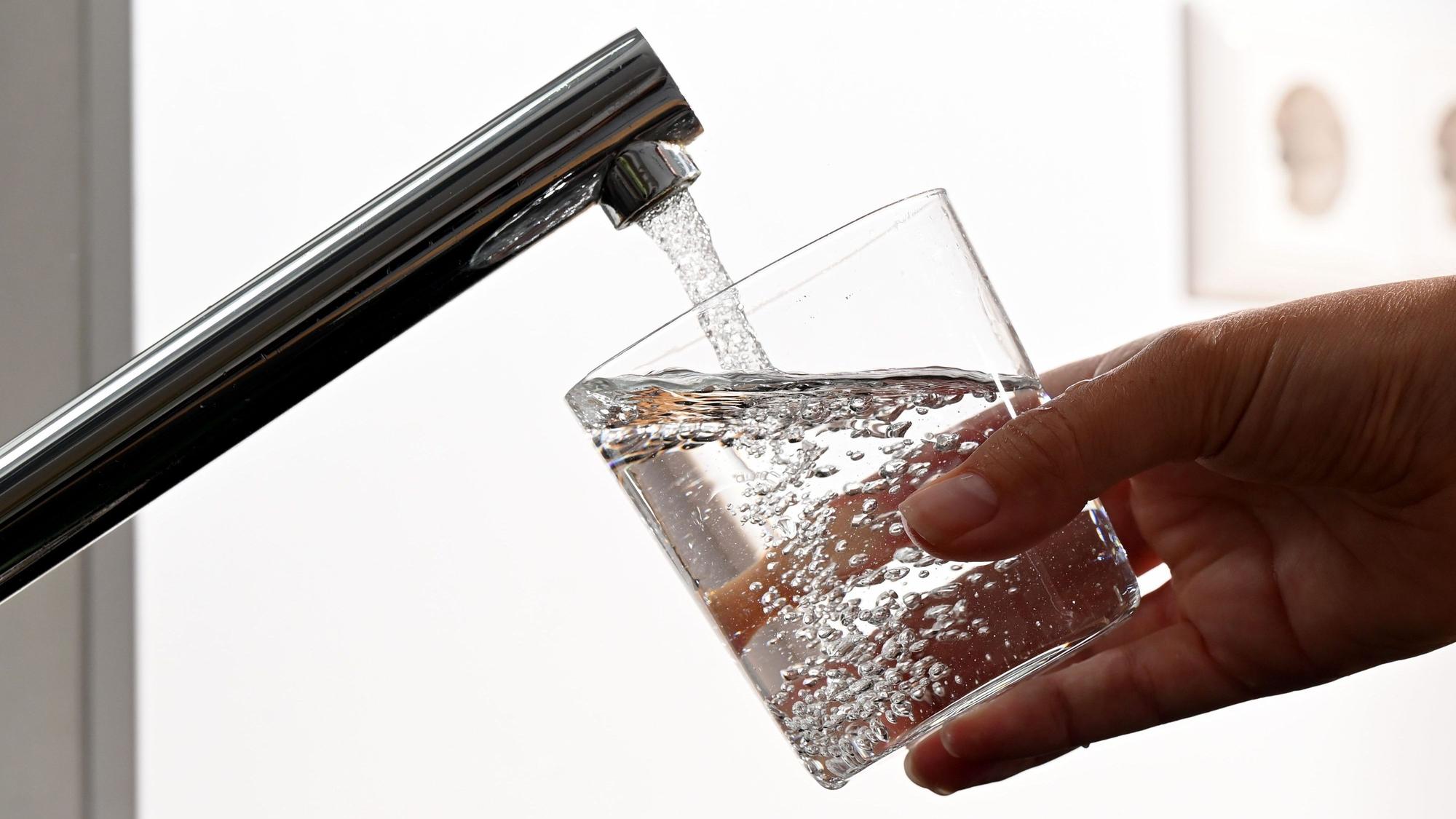 Wasser läuft aus einem Wasserhahn in ein Glas.