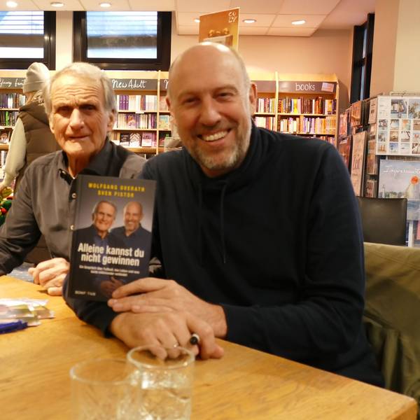 Zwei Männer an einem Tisch präsentieren ein Buch