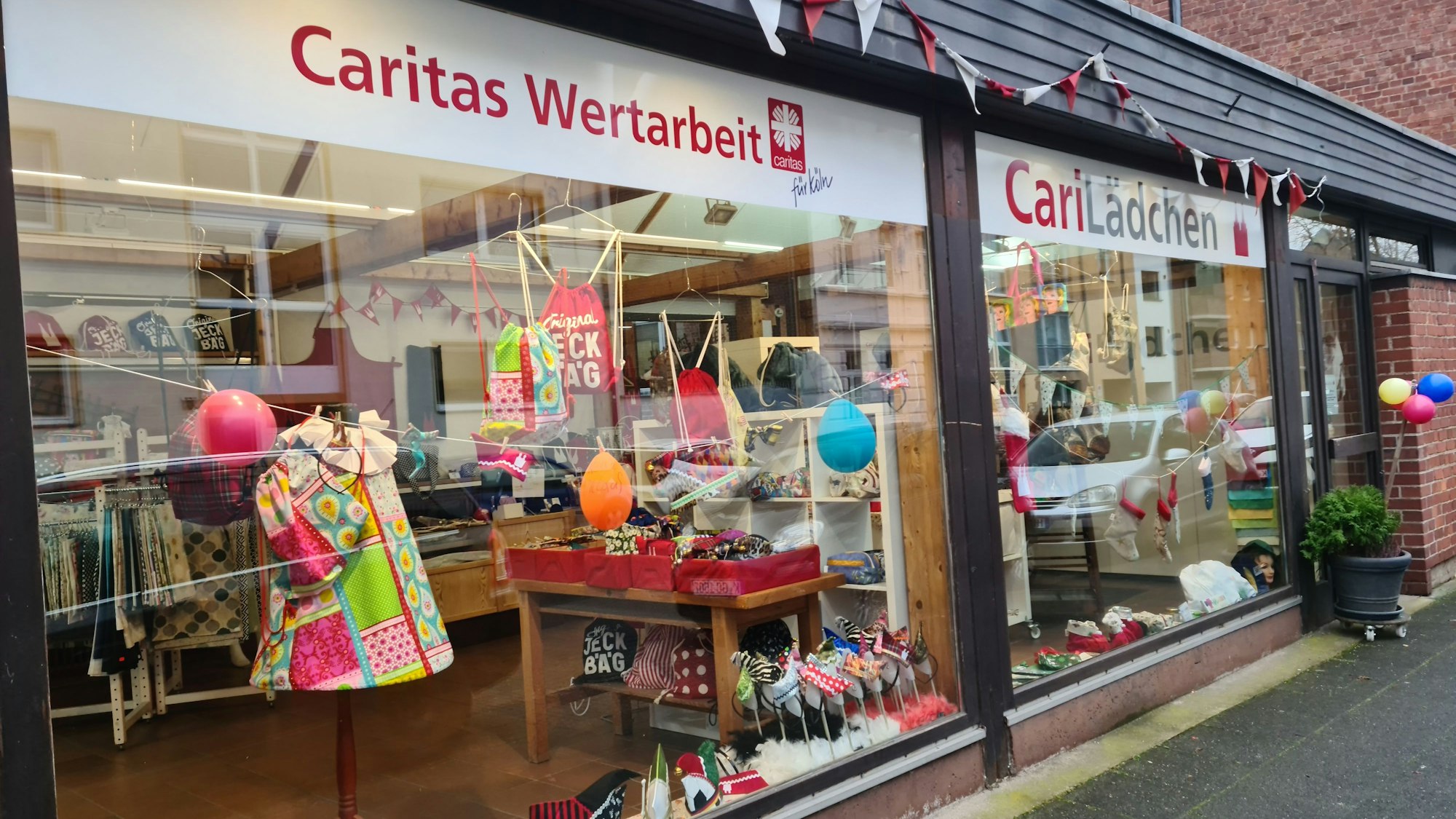 Im Schaufenster eines Ladens sind viele bunte Textil-Artikel zu sehen.