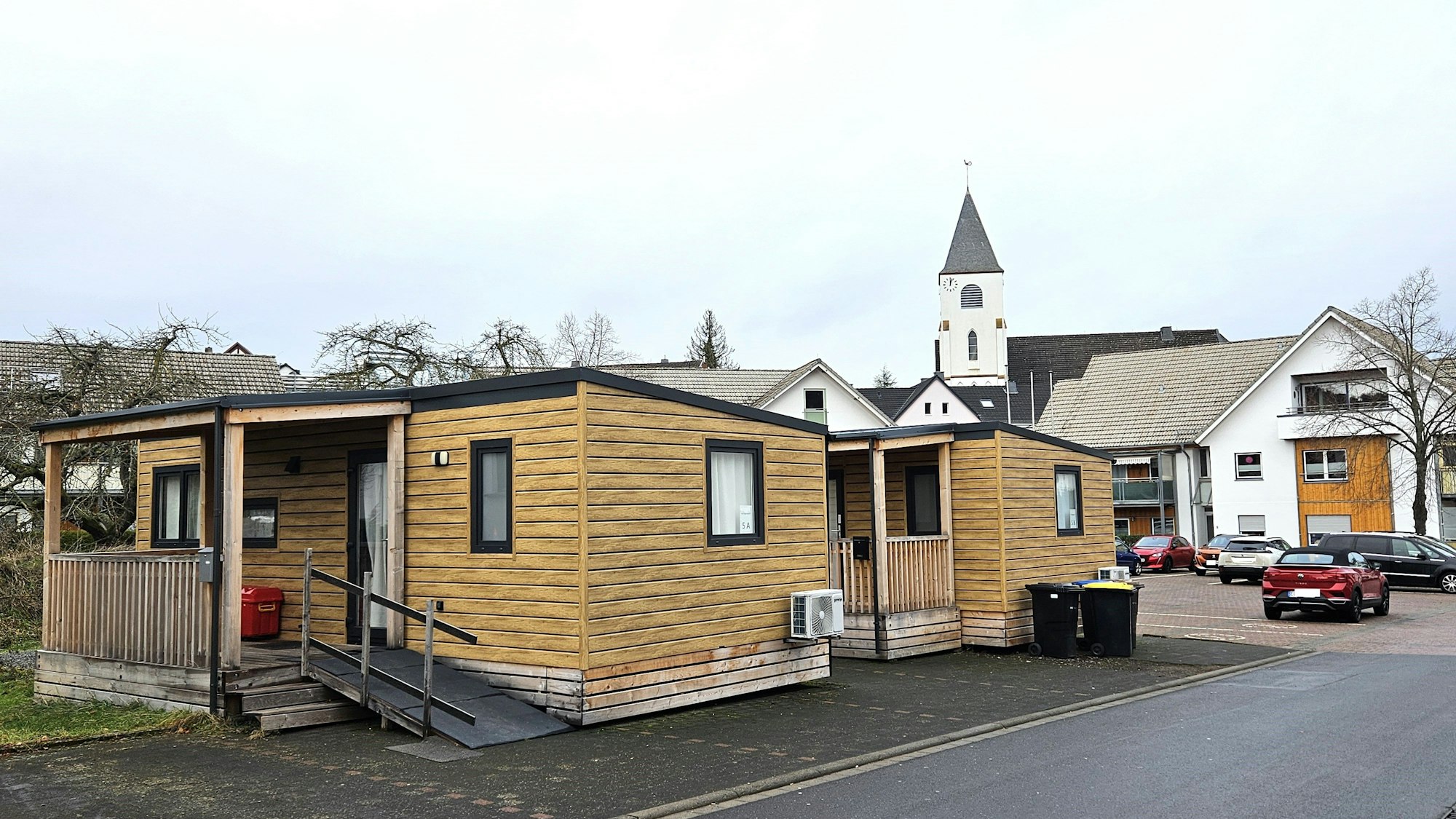 Blick auf zwei Tiny Houses, im Hintergrund ist die Kaller Kirche zu sehen.
