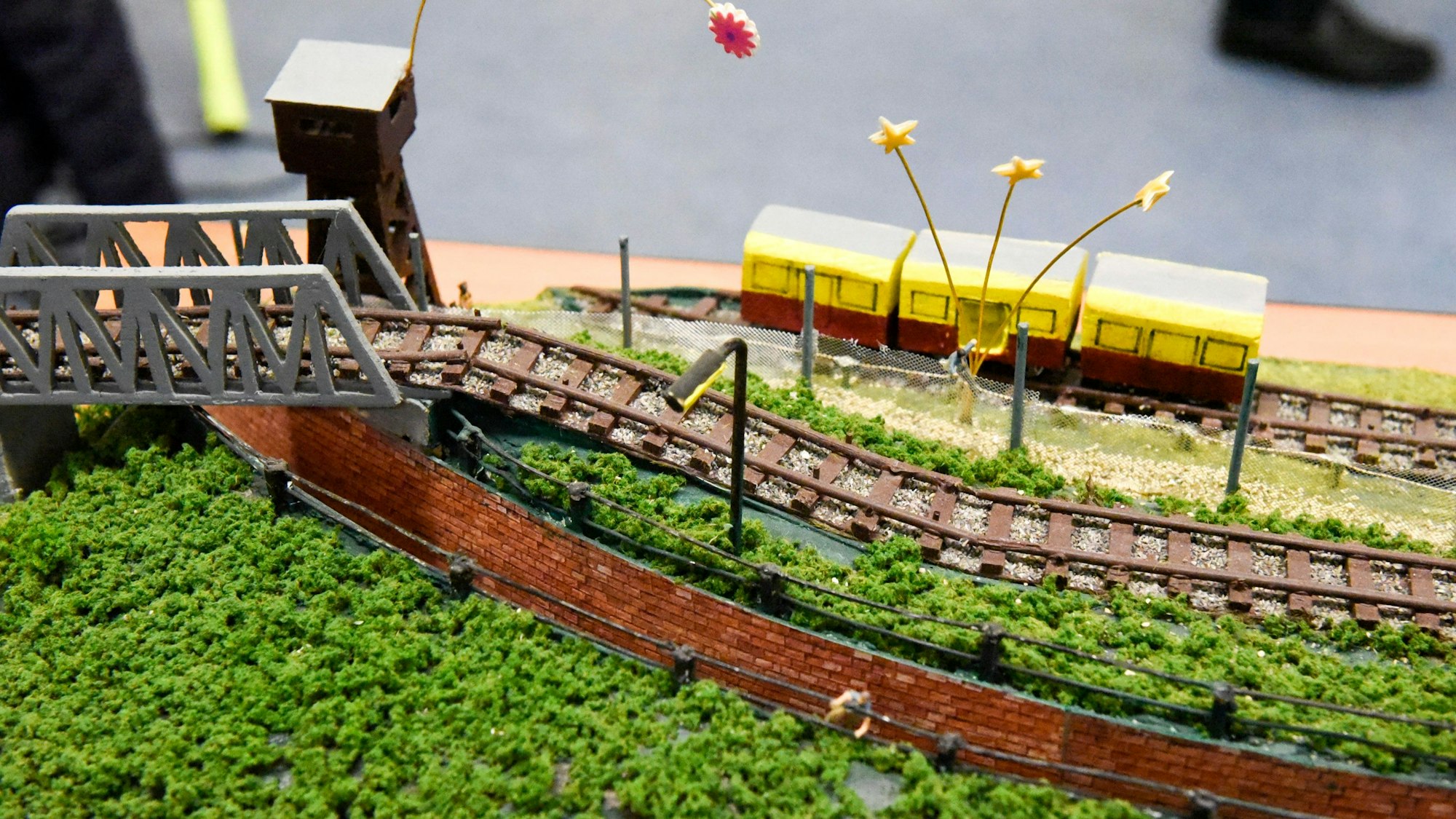 Im Kleinformat sieht man Bahngleise und einen Zug.