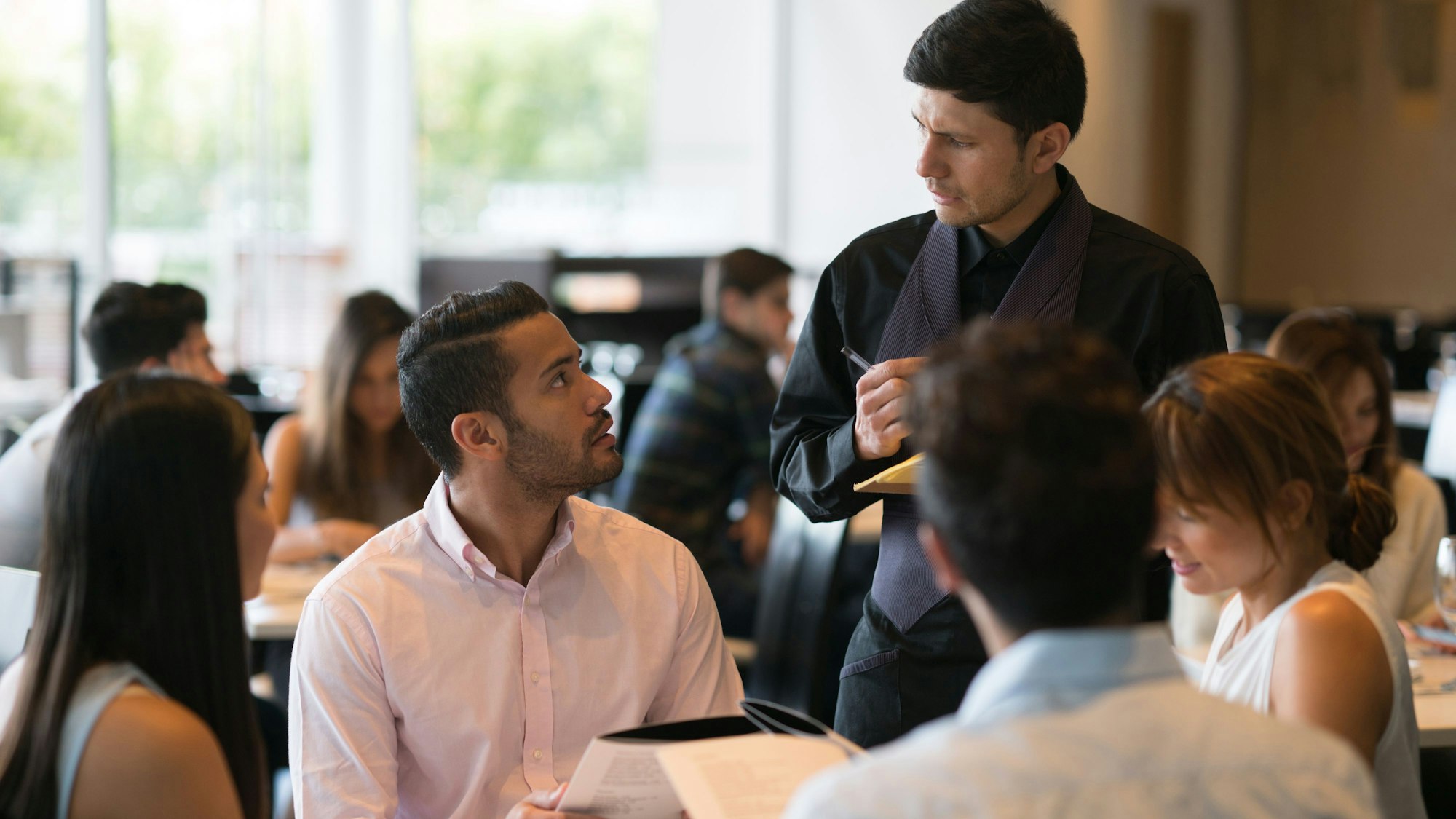 Ein Mann gibt im Restaurant bei einem Kellner eine Bestellung auf.