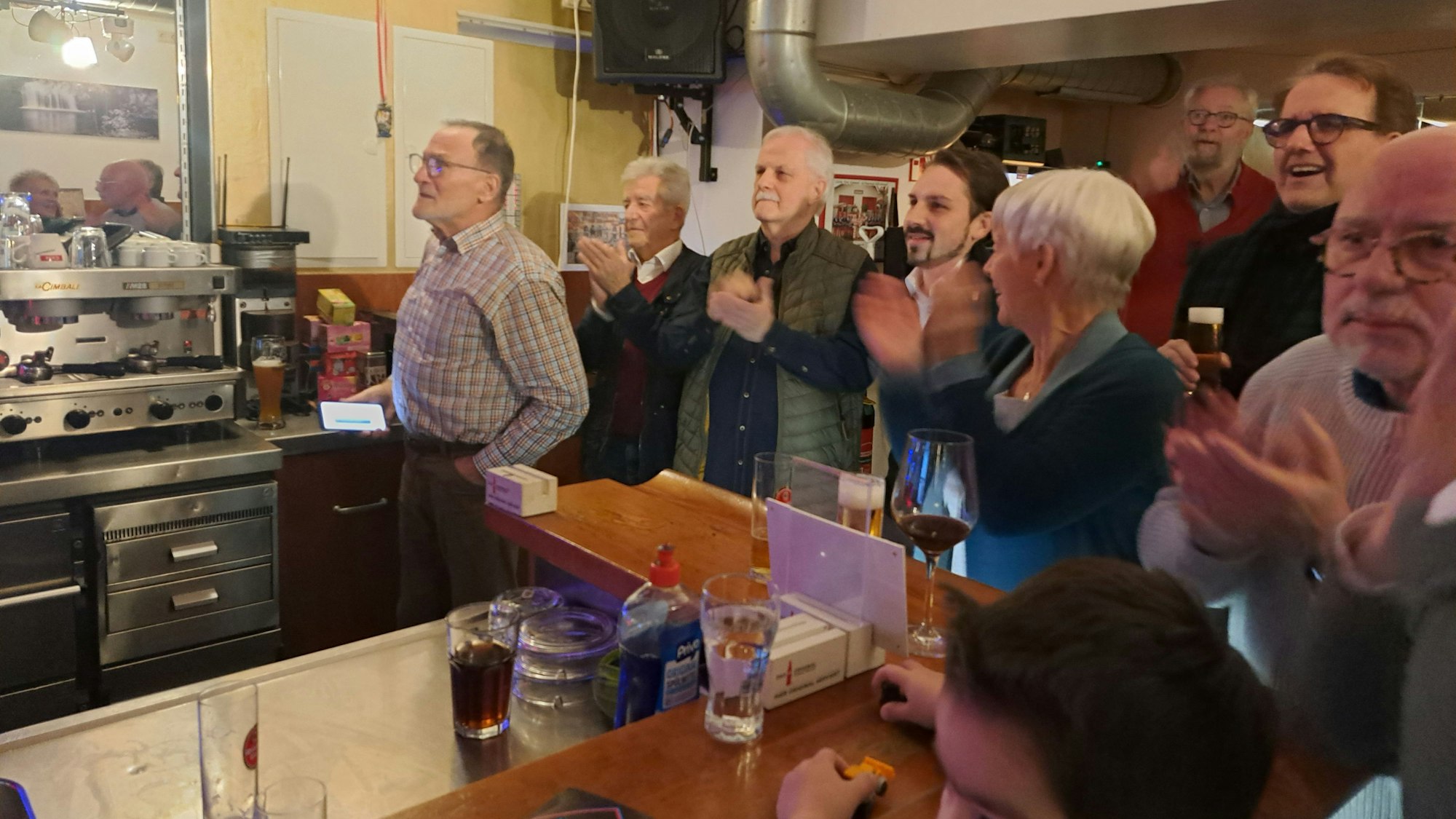 Klatschende Menschen stehen an einer Theke.