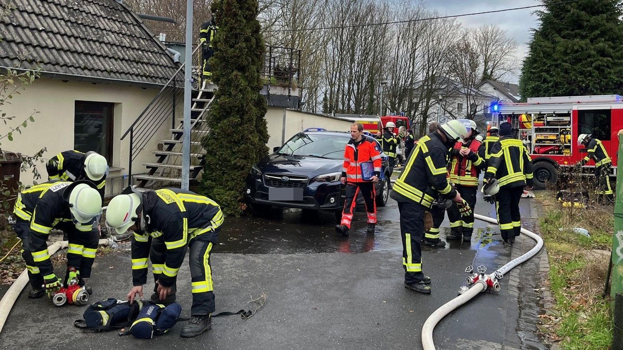 Mehrere Feuerwehrleute und Rettungskräfte in einer schmalen Straße.