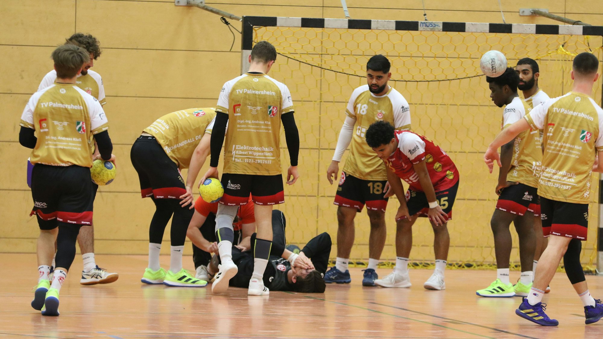 Der angeschlagene Lino Rübenach liegt auf dem Boden. Die Mitspieler stehen um ihn herum.