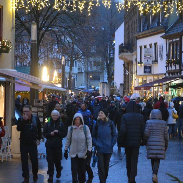 Menschen in dicken Jacken schlendern durch die weihnachtlich beleuchtete Innenstadt von Bad Münstereifel.