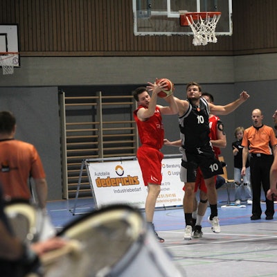 Matthias Zalfen blockt einen Ball. Im Vordergrund sind unscharf die Trommler der Erftbaskets zu erkennen.
