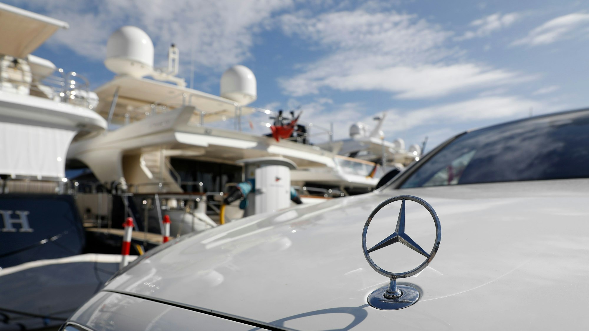 Eine Mercedes Limousine steht im Hafen von Puerto Portals vor Yachten.