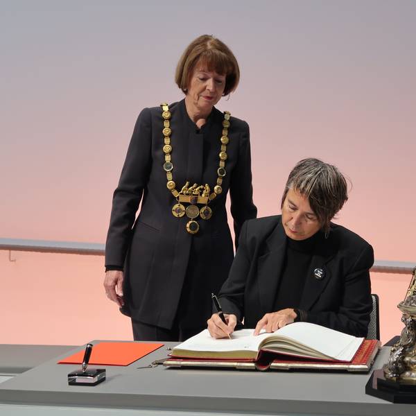 10.12.2023 Dr. Monika Hauser trägt sich in das goldene Buch der Stadt ein. Dabei OB Henriette Reker.